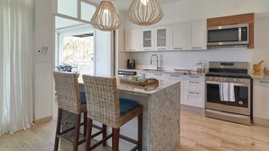 Una cocina moderna con una isla central, electrodomésticos de acero inoxidable y un ventanal grande.