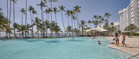 A pool area with palm trees and a view of the ocean.