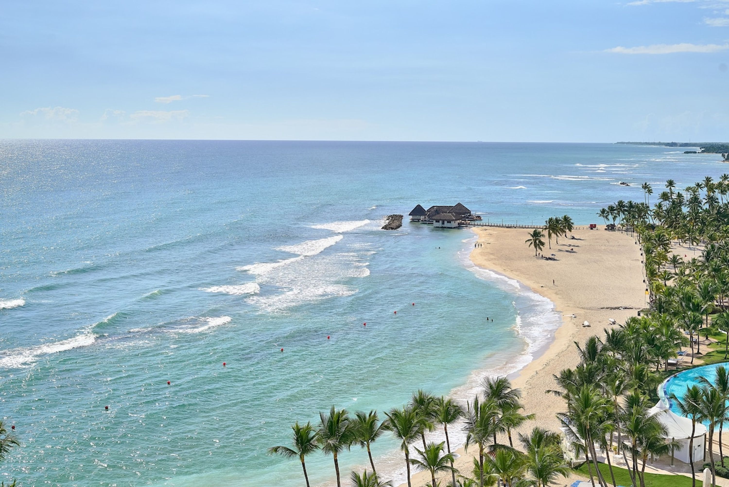 A beach resort with a pool, palm trees, and ocean views.