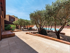A courtyard with a pool, surrounded by trees and a building with a red facade. - du Golf by Interhome (Saint Cyprien)