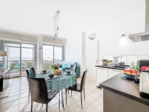 A dining area with a table set for two, a kitchen with a fruit bowl, and a balcony with a view. - Imperial II by Interhome (La Grande Motte)