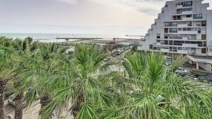Ein Küstengebäude im modernen Stil, Palmen im Vordergrund und Blick aufs Meer.