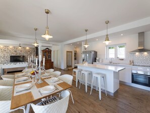 A modern kitchen with a central island, white bar stools, and pendant lighting. - Vacation home Olivia by Interhome (Šestanovac)