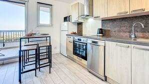 A modern kitchen with wooden cabinets, a dishwasher, an oven, and a sink. - Les Grenadines by Interhome (La Grande Motte)
