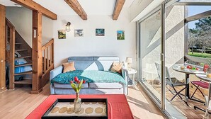 A modern living room with a sofa, a coffee table, and a dining area with a table and chairs. - Les Jardins de la Plage by Interhome (Carnac)