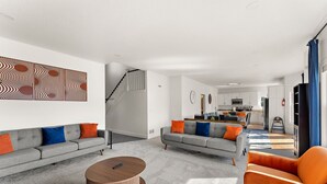 Una sala de estar moderna con dos sofás, una mesa de centro y una escalera que lleva a una cocina.