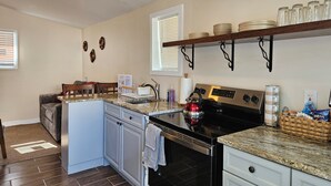 A kitchen with a stove, oven, and sink. There are cabinets, a countertop, and a window with blinds. - Enjoy a piece of home in a cozy inviting space. (Waynesboro)