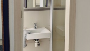 Un baño con lavamanos, espejo y ducha.