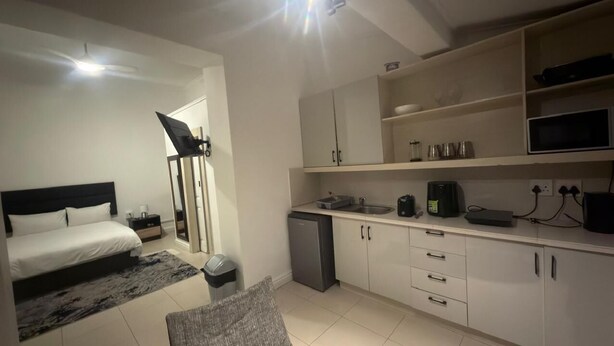 Un dormitorio con cama, escritorio, microondas y refrigerador pequeño.