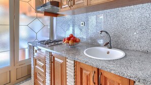 A kitchen with wooden cabinets, a granite countertop, a stainless steel sink, and a hexagonal window. - Milanković by Interhome (Vrsar)