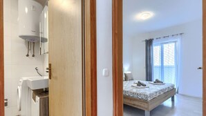 A bedroom with a bed, a window, and a bathroom with a sink and a washing machine. - Milanković by Interhome (Vrsar)