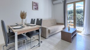 A modern living room with a dining table, sofa, and a balcony with a view. - Milanković by Interhome (Vrsar)