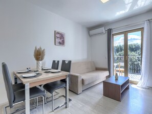 A modern living room with a dining table, sofa, and a balcony with a view. - Milanković by Interhome (Vrsar)
