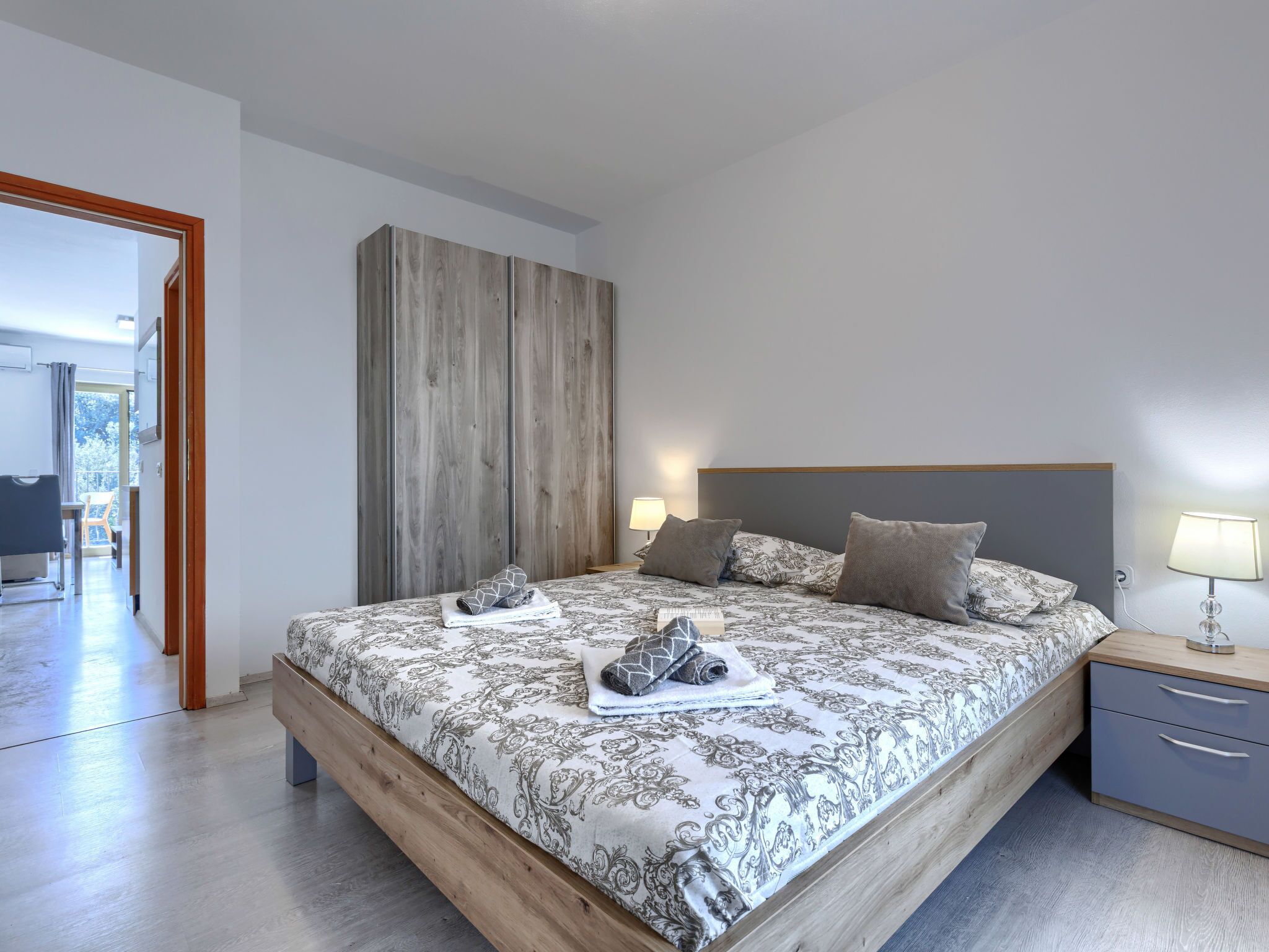 A bedroom with a bed, bedside tables, and a view of the outside.