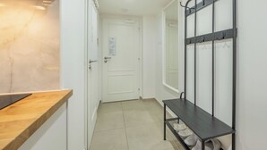 A hallway with a wooden bench, a coat rack, and a white door. - Čelakovsky by Interhome (Prague centre)