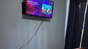 A television mounted on a wall displaying an OS update screen, a wooden bench, and a patterned rug.
