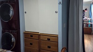 A bedroom with a bed, a wardrobe, a washing machine, and a desk.