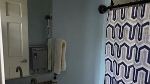 A bathroom with a sink, mirror, towel rack, toilet, and shower curtain.