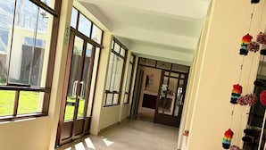 A corridor with large windows, a tiled floor, and a wall with a decorative rope. - Boutique Inka Hotel (Ollantaytambo)
