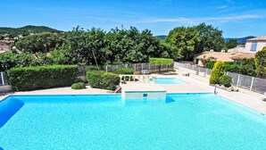 A large outdoor swimming pool with clear blue water, surrounded by a fence and greenery. - Les Mas de Cogolin by Interhome (Cogolin)