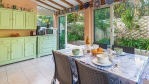 A kitchen with a dining area, wooden beams, and a view of greenery. - Les Mas de Cogolin by Interhome (Cogolin)