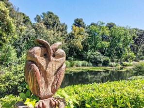 A wooden sculpture of an owl in a park with a pond and lush greenery in the background. - Les Rivages de Coudoulière by Interhome (Six Fours La Coudoulière)