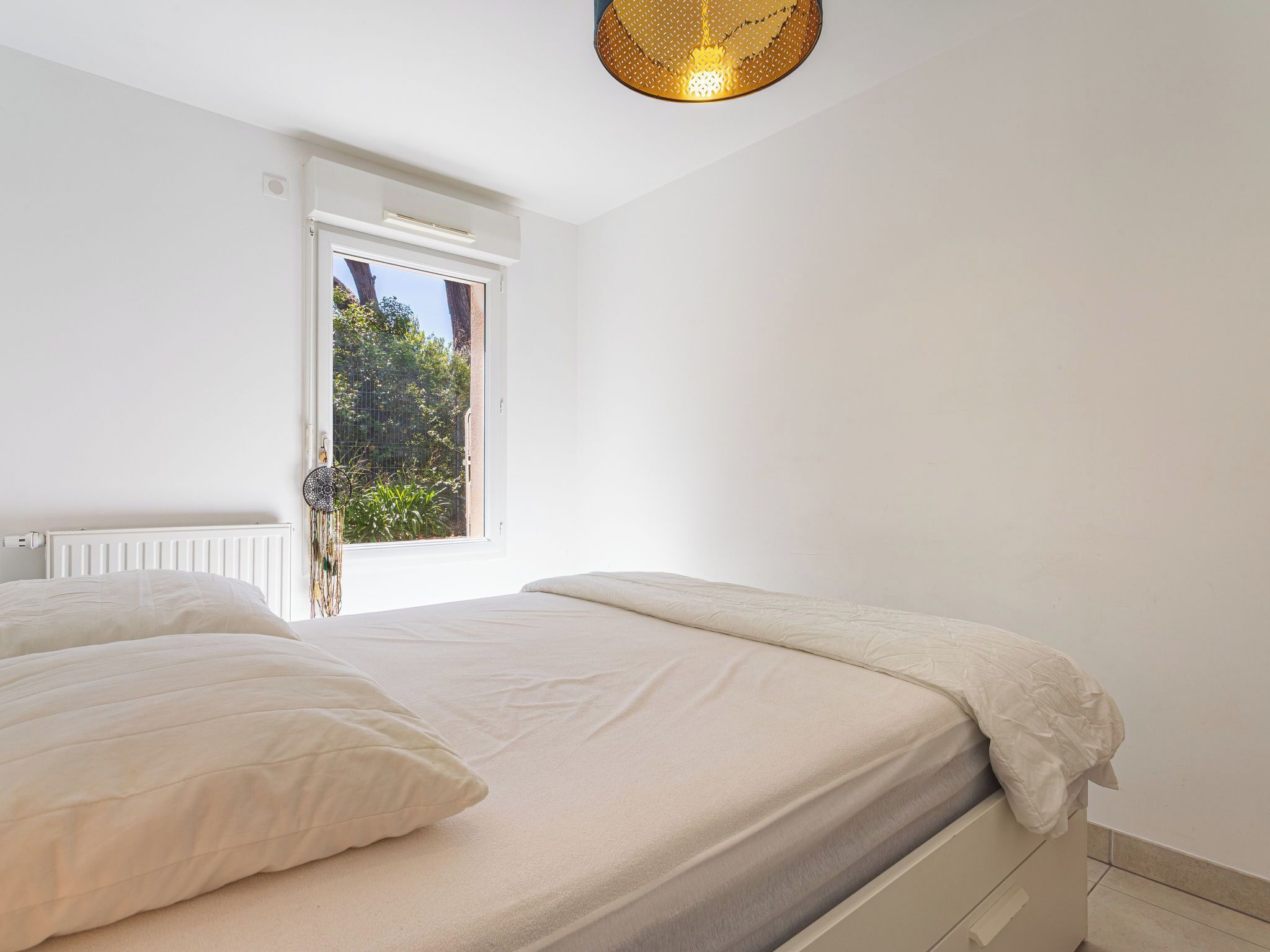 Een slaapkamer met een bed, een raam en een radiator.
