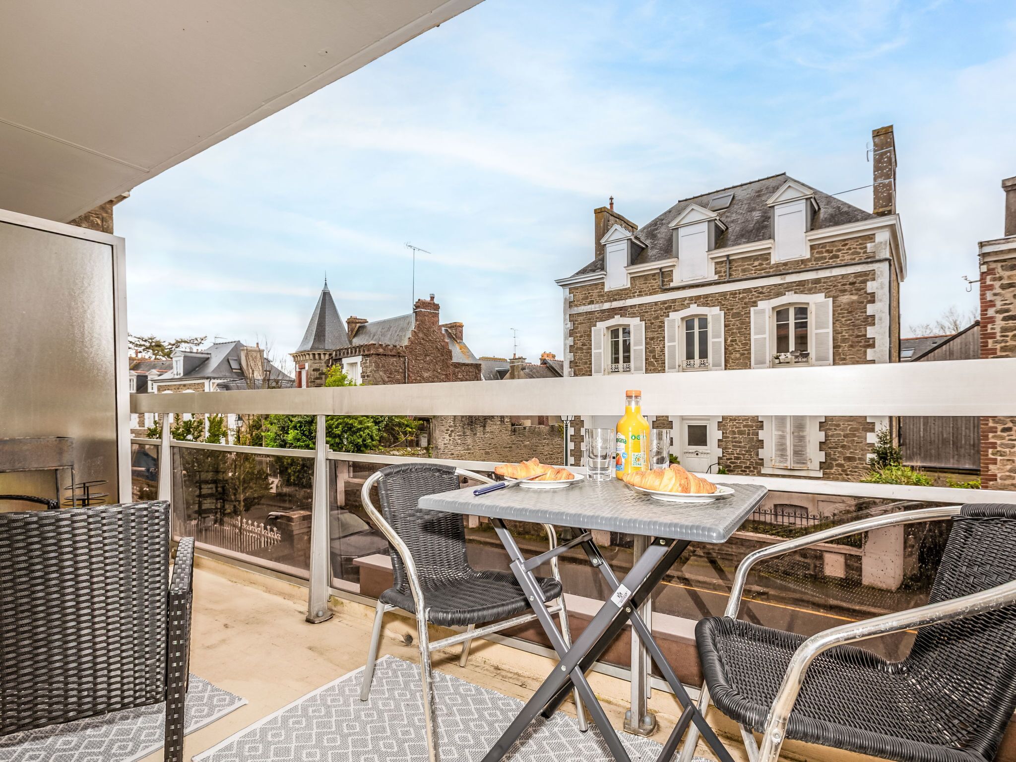 Ein Balkon mit Tisch, Stühlen und einer Orangensaftflasche.