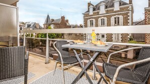 A balcony with a table, chairs, and a bottle of orange juice. - L'Albatros by Interhome (Dinard)