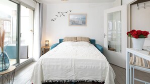 A bedroom with a bed, a wall-mounted light fixture, a window, and a door. - L'Albatros by Interhome (Dinard)