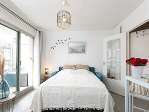 A bedroom with a bed, a wall-mounted light fixture, a window, and a door. - L'Albatros by Interhome (Dinard)