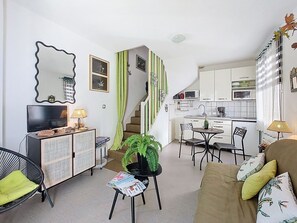 A compact living space with a kitchenette, a dining area, and a seating area with a sofa and chairs.