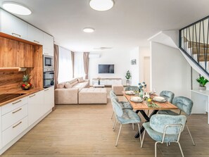 Eine moderne Wohnung mit Essbereich, Sofa, Küche und Treppe.