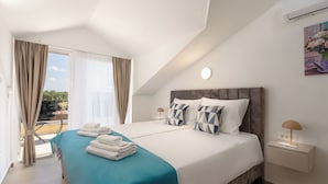 A hotel room with a bed, a nightstand, a lamp, a painting, and a view of the outdoors. - Mediterranee Oliva by Interhome (Poreč/Funtana)