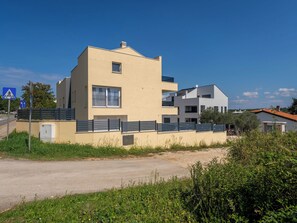 Un moderno edificio residencial de dos pisos con techo plano, un pequeño balcón y un acceso con reja.