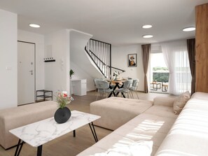 Ein modernes Wohnzimmer mit einer Couch, einem Esstisch und einer Treppe.