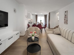 A modern living room with a sofa, a TV, a dining area, and a staircase. - Mediterranee Oliva by Interhome (Poreč/Funtana)