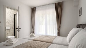 A hotel room with two beds, a bathroom with a marble wall, and sheer curtains on the window. - Mediterranee Oliva by Interhome (Poreč/Funtana)
