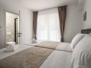 A hotel room with two beds, a bathroom with a marble wall, and sheer curtains on the window. - Mediterranee Oliva by Interhome (Poreč/Funtana)