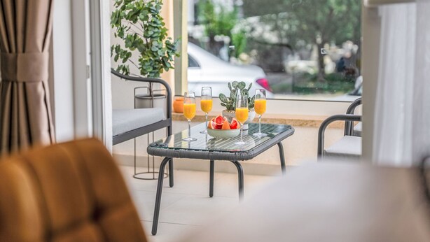 A balcony with a glass table, two chairs, a sofa, and a potted plant. - Mediterranee Oliva by Interhome (Poreč/Funtana)
