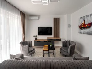 A modern living room with a sofa, two armchairs, a coffee table, a TV, and a painting on the wall. - Mediterranee Oliva by Interhome (Poreč/Funtana)