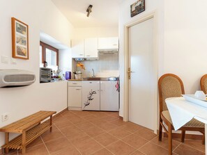 Una cocina compacta con horno empotrado, un pequeño comedor con mesa y sillas, y un banco.