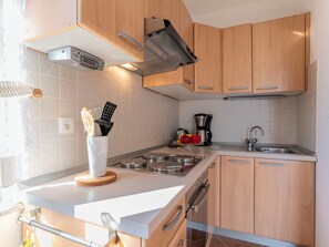 Una cocina moderna con armarios de madera, un lavamanos de acero inoxidable, una cafetera y una estufa.