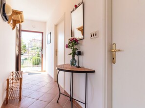 Ein Flur mit einem Holzregal, einem Spiegel, einer Vase mit Blumen und einer Tür.