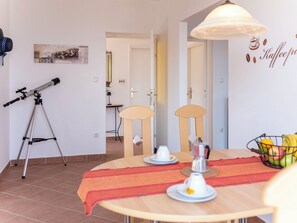 Ein Essbereich mit einem Tisch für zwei Personen, einem Teleskop und einer Wand mit Kaffeemotiv.