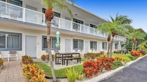 A hotel with a two-story structure, outdoor seating, palm trees, and a well-maintained garden. - Modern Cozy Beach Studio #17 (Pompano Beach)
