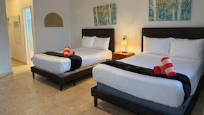 A hotel room with two beds, a ceiling fan, artwork on the walls, and a door leading to another room. - Comfortable Studio • 5-Min Walk to Beach #18 (Pompano Beach)