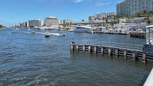 Un puerto deportivo con barcos, un muelle y un gran edificio de hotel al fondo.