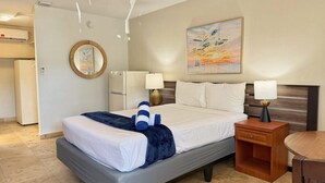 Habitación de hotel con cama, mesitas de noche, lámpara, un cuadro y equipo de aire acondicionado.