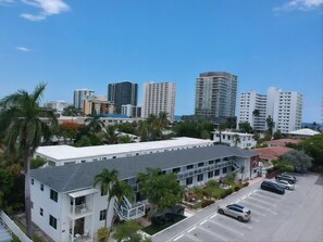 Un edificio a più piani con tetto piatto, circondato da palme e un parcheggio.